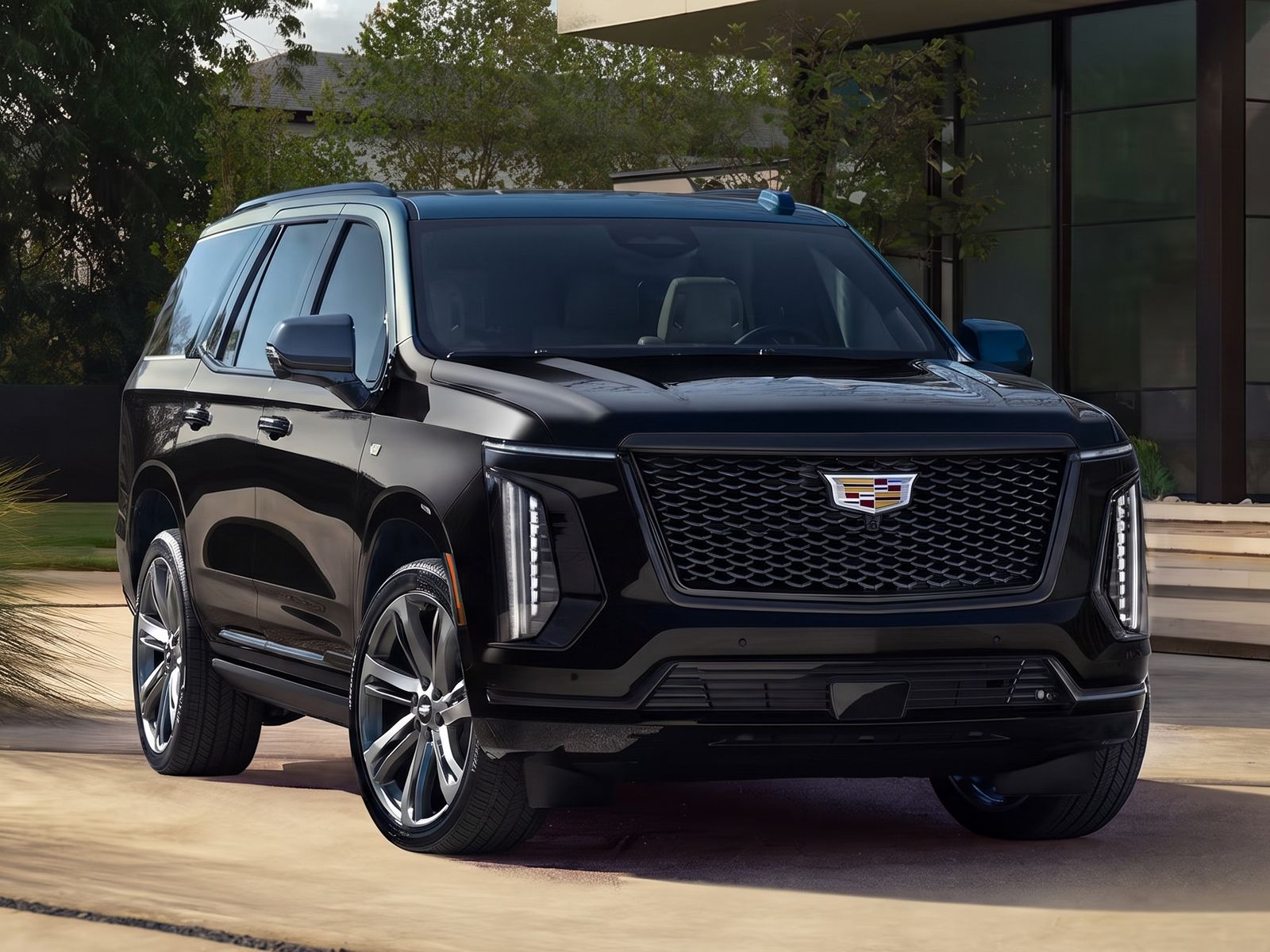 Black Cadillac Escalade parked in a sunlit driveway outside a modern home